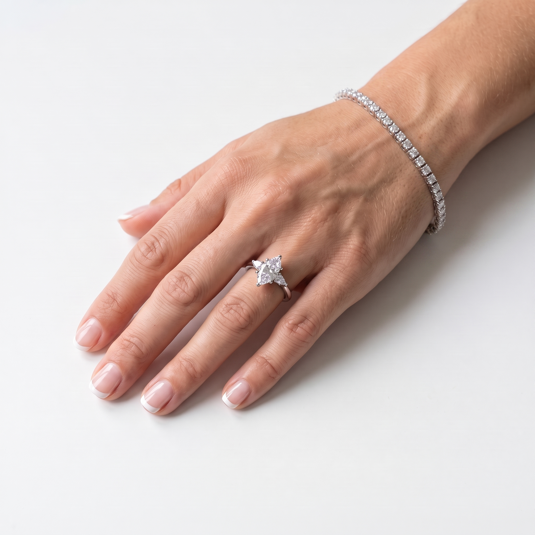 Marquise engagement ring with pear accents worn on the left hand, white gold shown