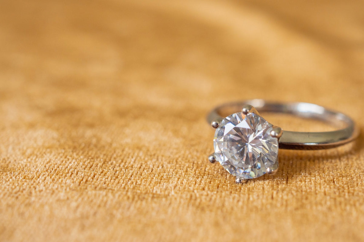 Round diamond solitaire engagement ring on gold fabric