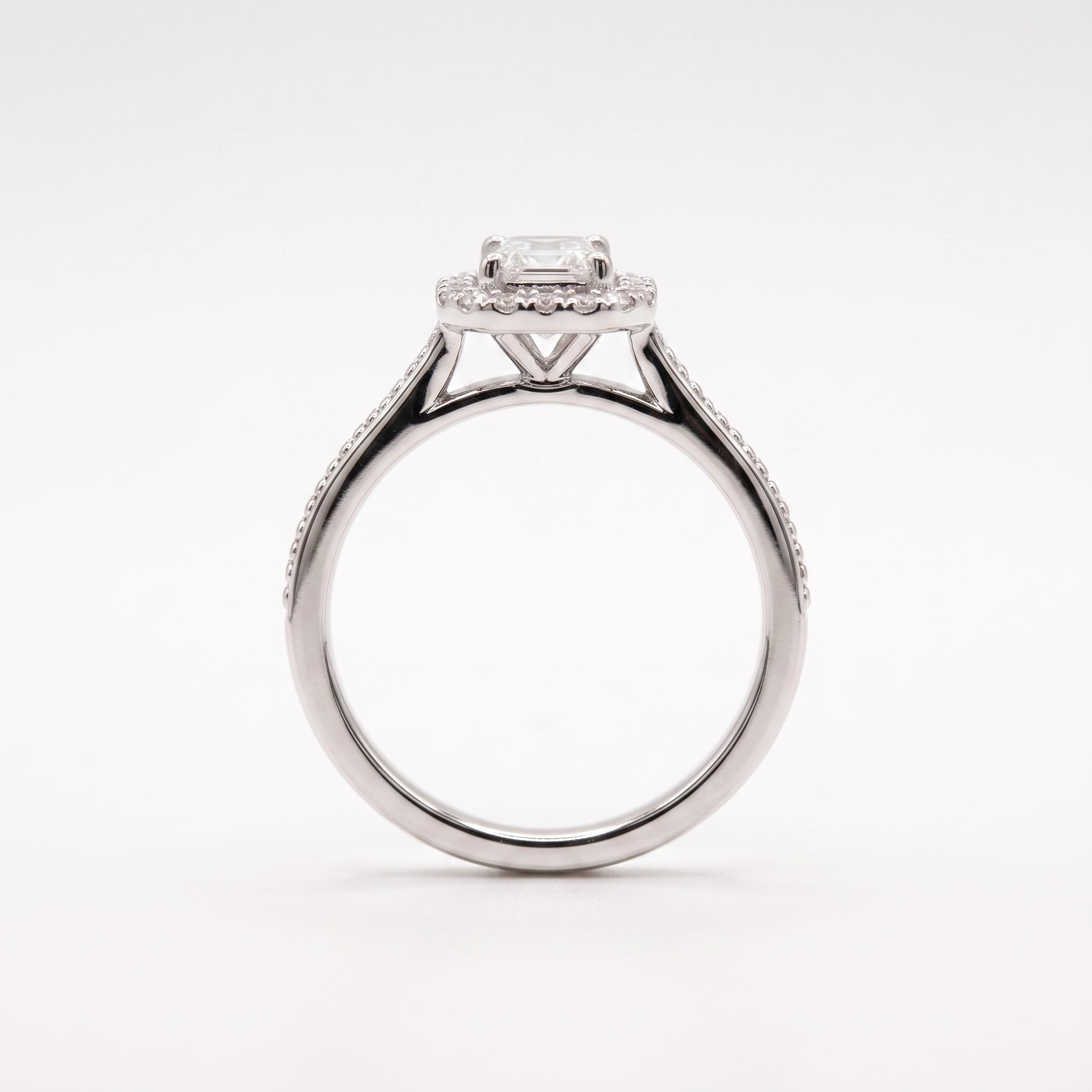 Emerald-cut halo engagement ring, side profile, white gold shown