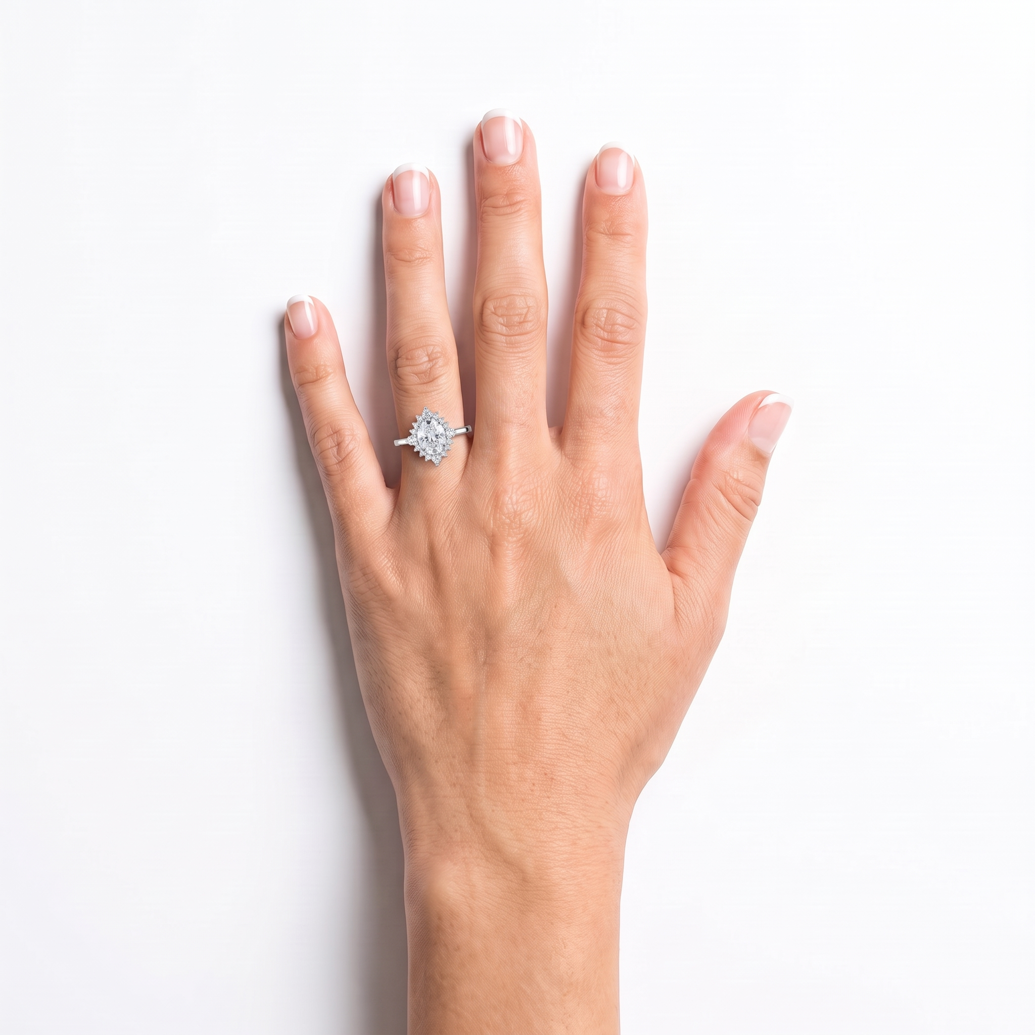 Oval halo engagement ring worn on the left hand, white gold shown