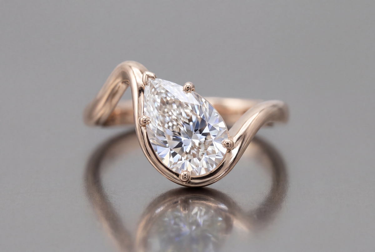 Pear-cut white diamond in an asymmetrical rose-gold freeform engagement ring.